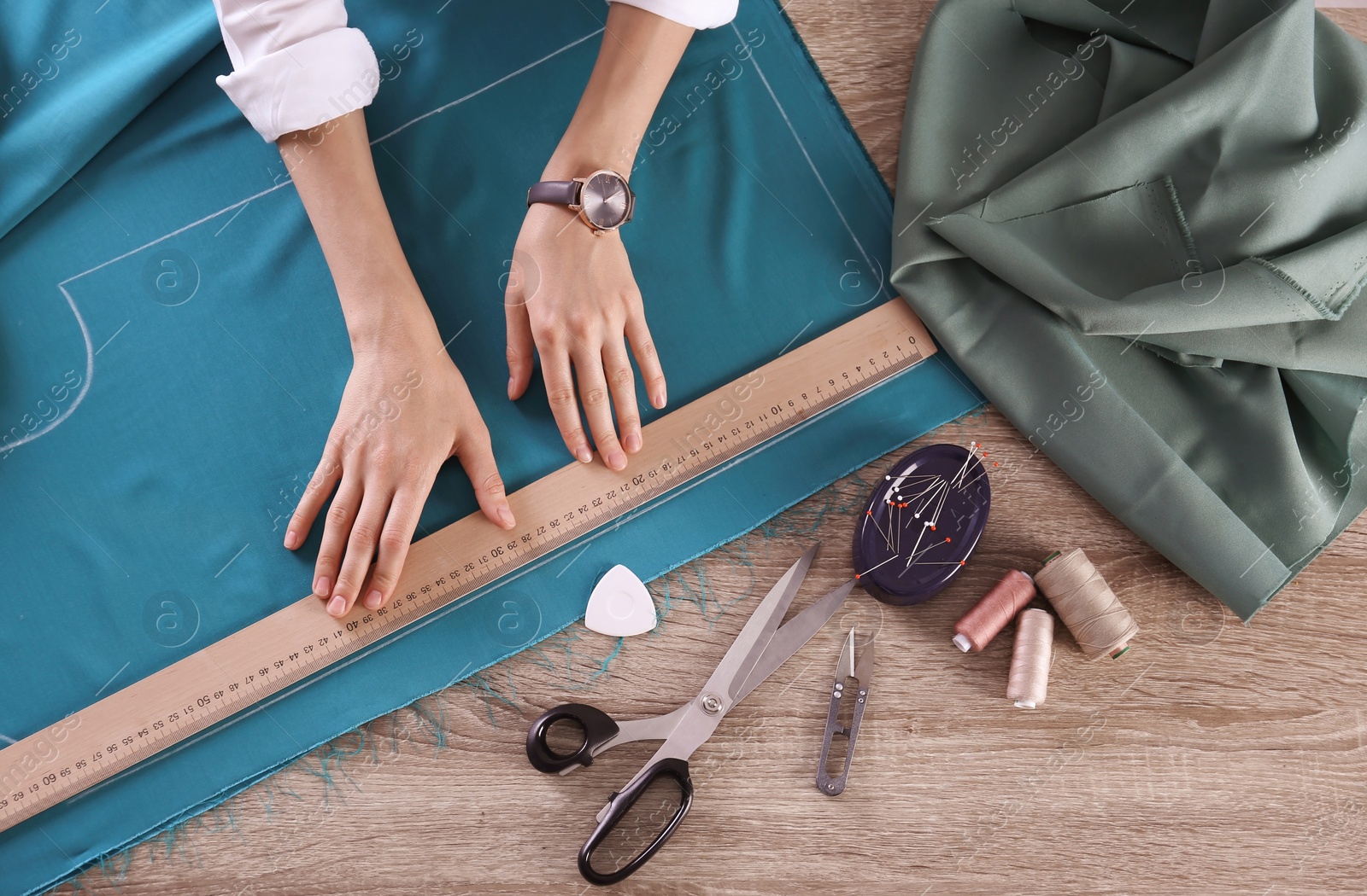 Photo of Tailor working with cloth at table in atelier, top view