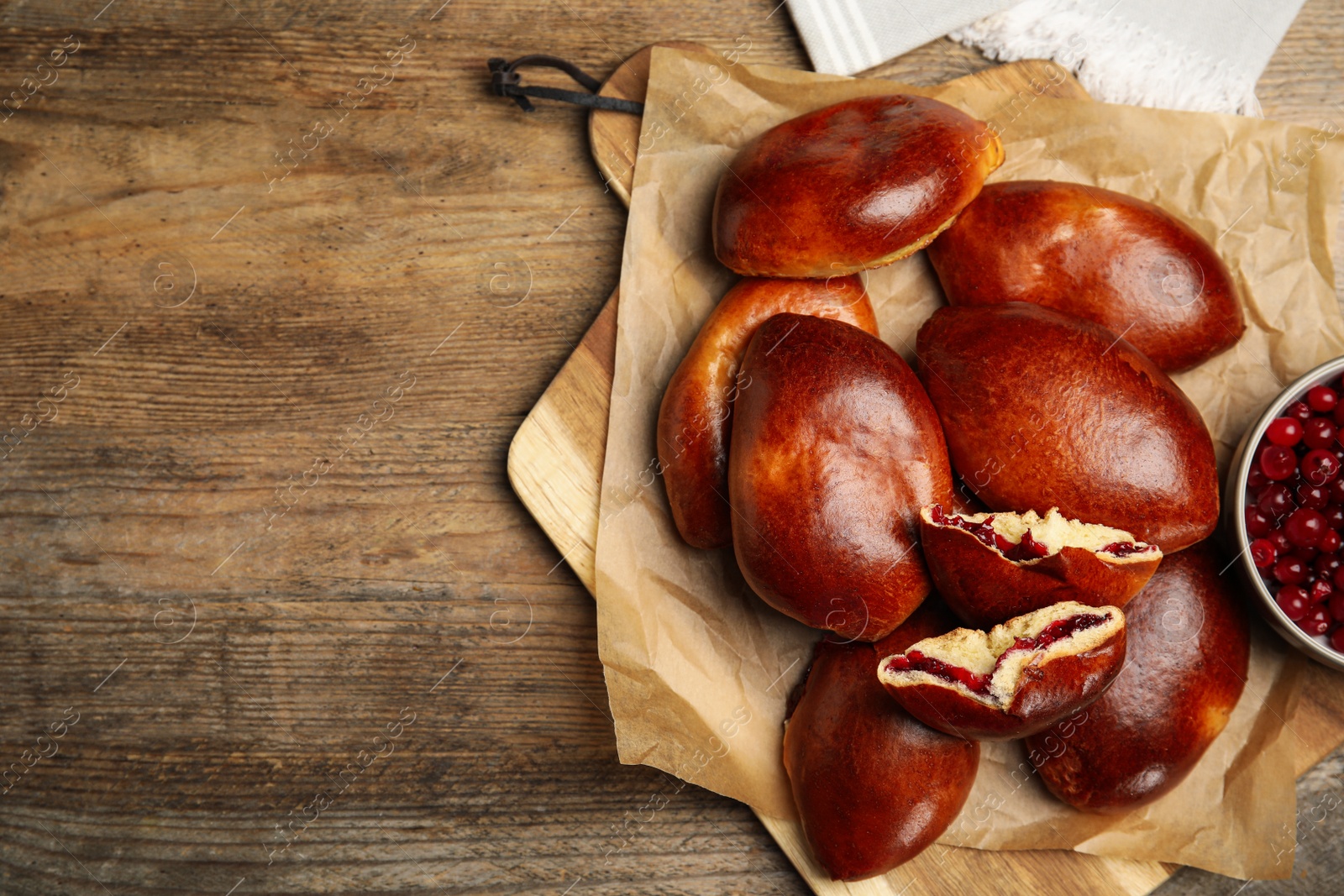 Photo of Delicious baked cranberry pirozhki on wooden table, flat lay. Space for text