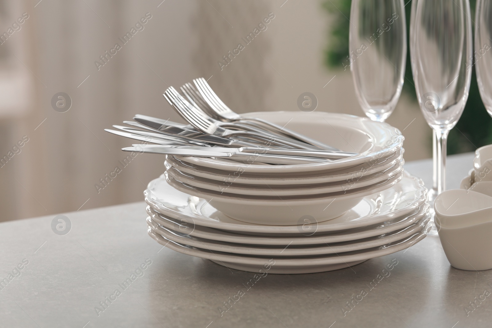 Photo of Set of clean dishware, cutlery and champagne glasses on table indoors