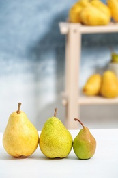 Photo of Fresh ripe pears on light table against blurred background