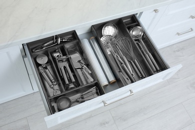 Photo of Open drawer with stainless steel utensil set. Order in kitchen