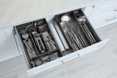 Open drawer with stainless steel utensil set. Order in kitchen