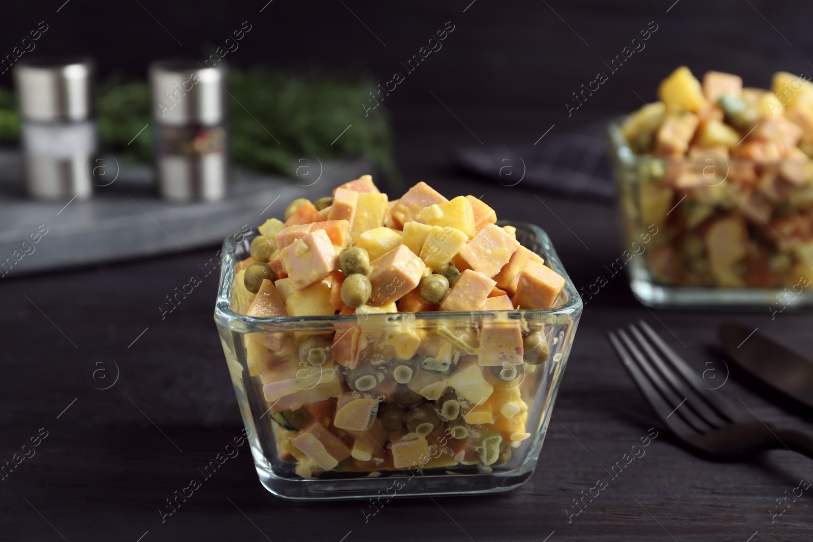 Photo of Delicious russian salad Olivier served on black wooden table