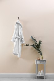 Soft comfortable bathrobe hanging on beige wall indoors