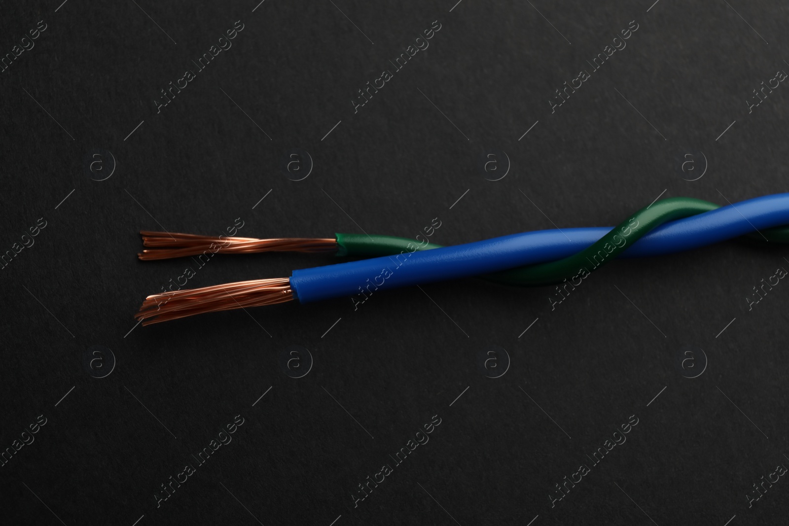 Photo of Two twisted electrical wires on black background, closeup