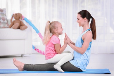 Photo of Sportive woman doing fitness exercises with daughter at home