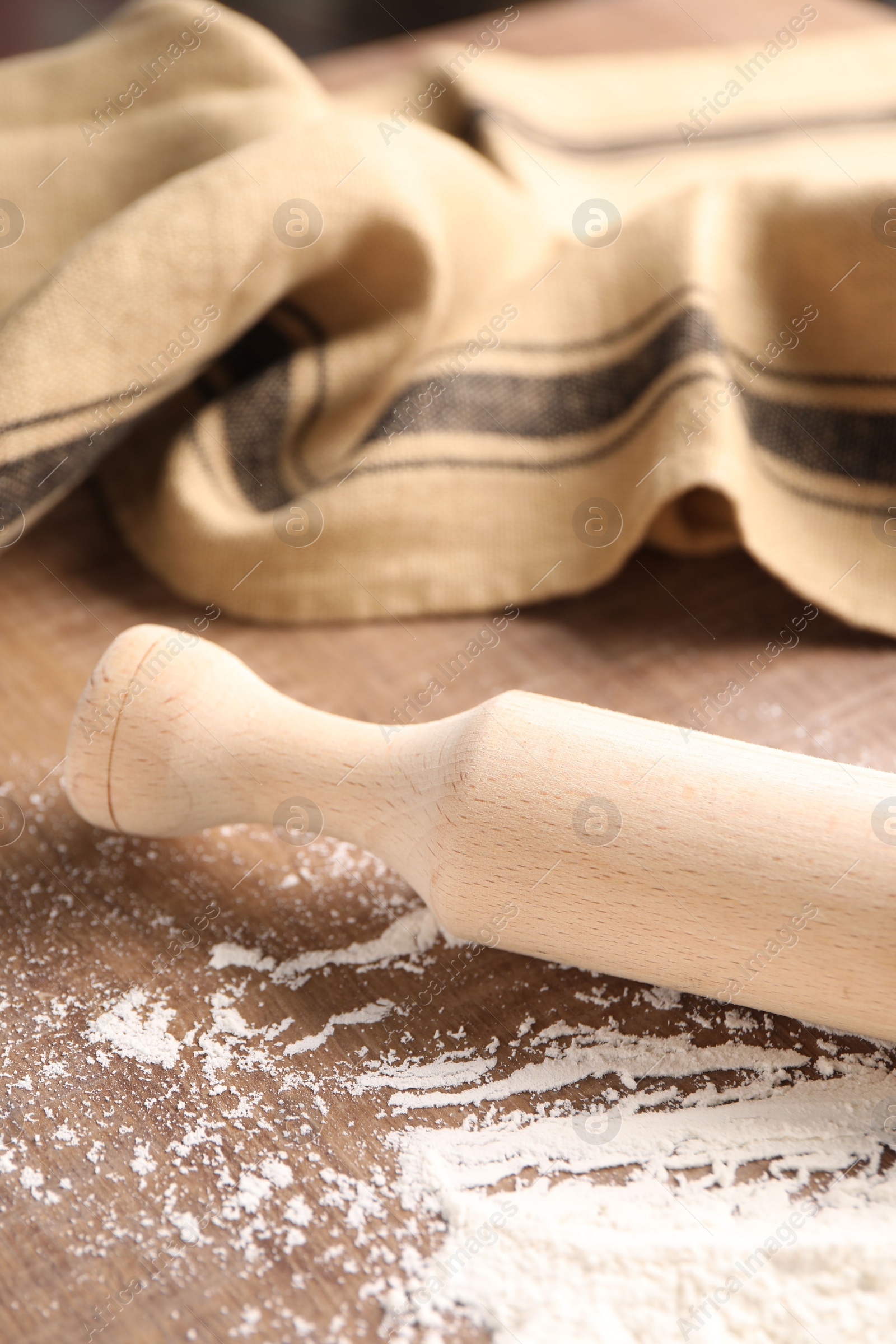 Photo of Scattered flour and rolling pin on wooden table, closeup