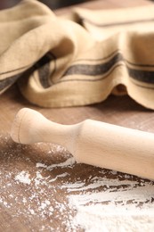 Photo of Scattered flour and rolling pin on wooden table, closeup