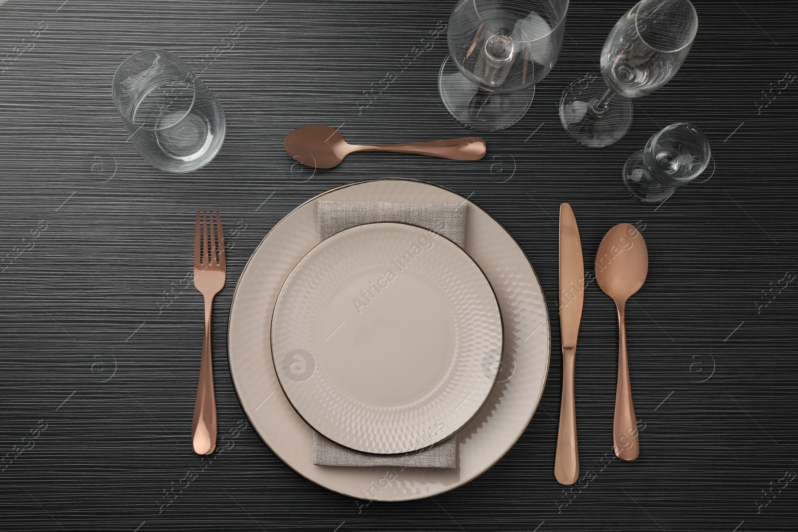 Photo of Stylish setting with cutlery, glasses and plates on black wooden table, flat lay