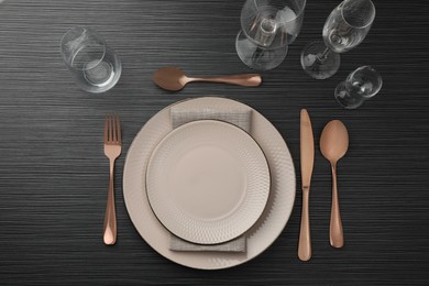 Stylish setting with cutlery, glasses and plates on black wooden table, flat lay