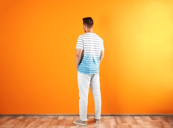 Photo of Young man in stylish jeans near color wall