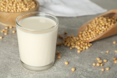 Glass with fresh soy milk and grains on grey table