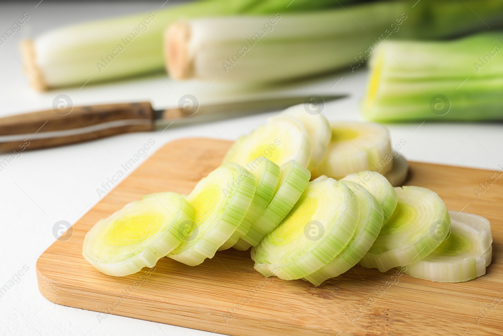 Photo of Fresh raw leek on cutting board, closeup. Ripe onion