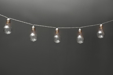 Photo of Garland of lamps with light bulbs on grey background