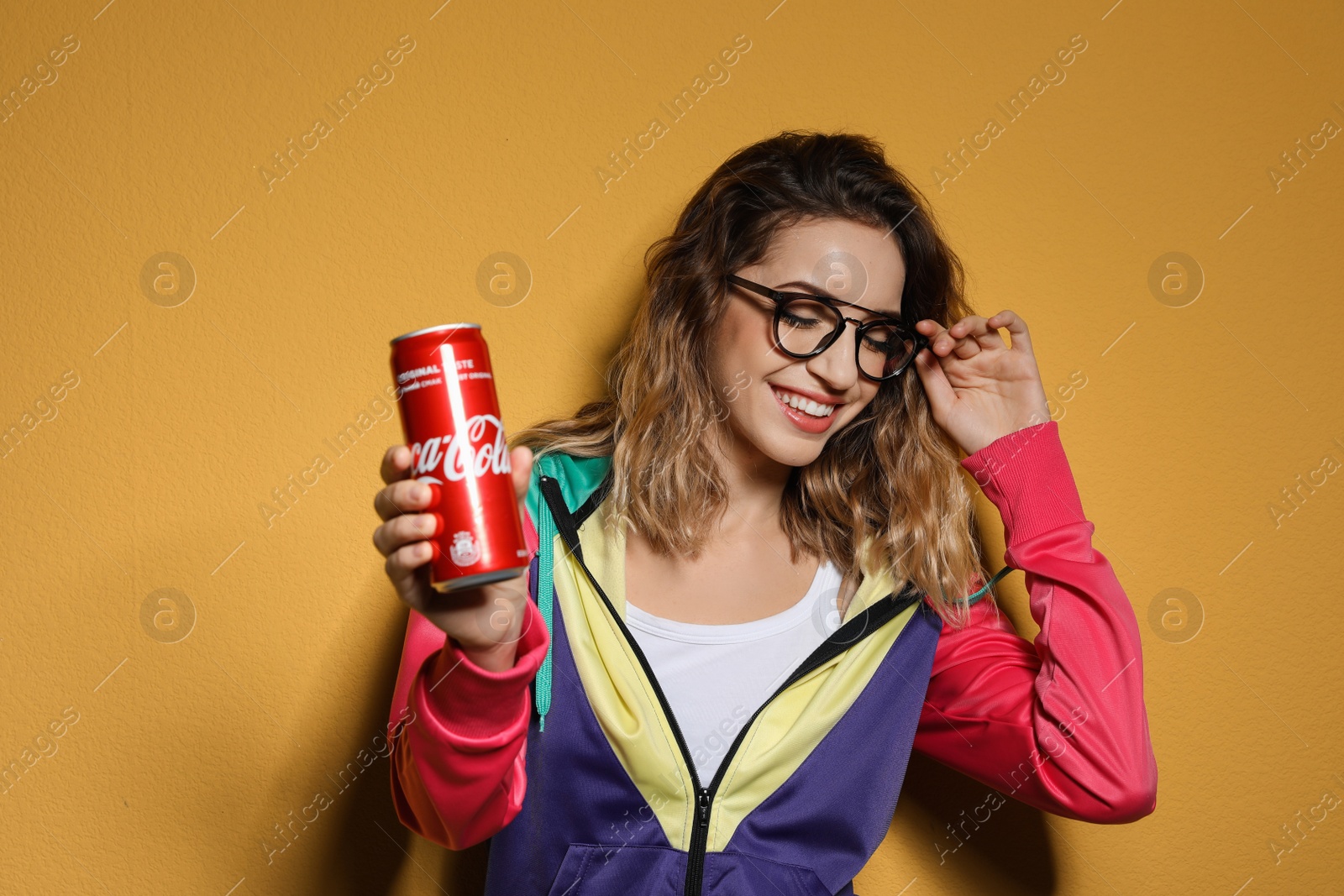 Photo of MYKOLAIV, UKRAINE - NOVEMBER 28, 2018: Young woman with Coca-Cola can on color background