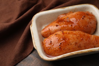 Photo of Raw marinated chicken fillets on wooden table