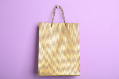 Photo of Gold shopping paper bag on violet background