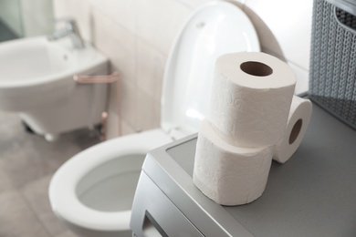 Photo of Toilet paper rolls on washing machine in water closet. Space for text