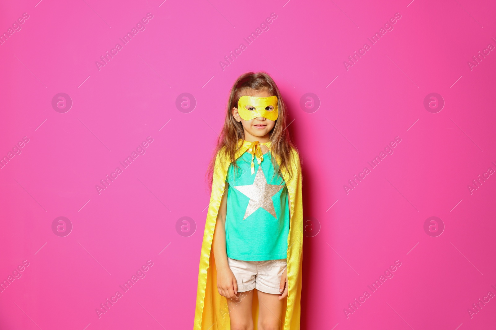 Photo of Adorable little child playing superhero on color background. Indoor recreation