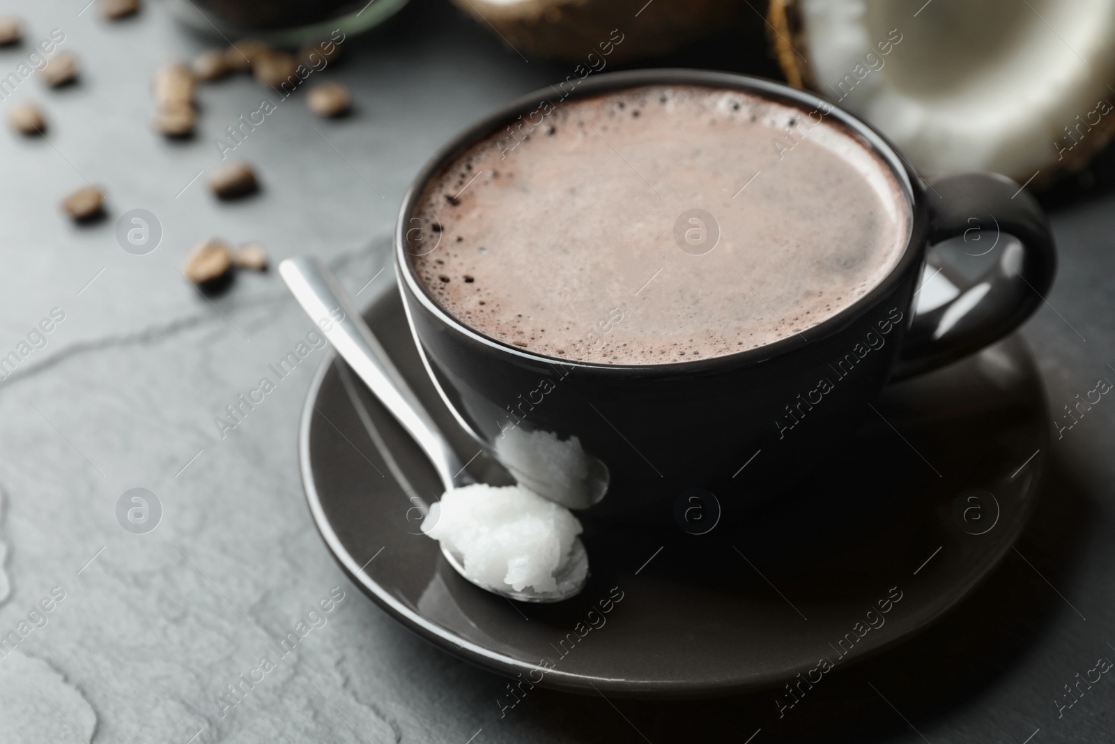 Photo of Delicious coffee with organic coconut oil on grey table