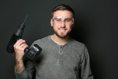 Photo of Young working man with power drill on dark background