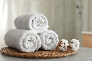 Photo of Clean rolled towels and cotton flowers on table in bathroom