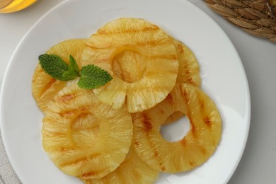 Tasty grilled pineapple slices with mint on white table, top view