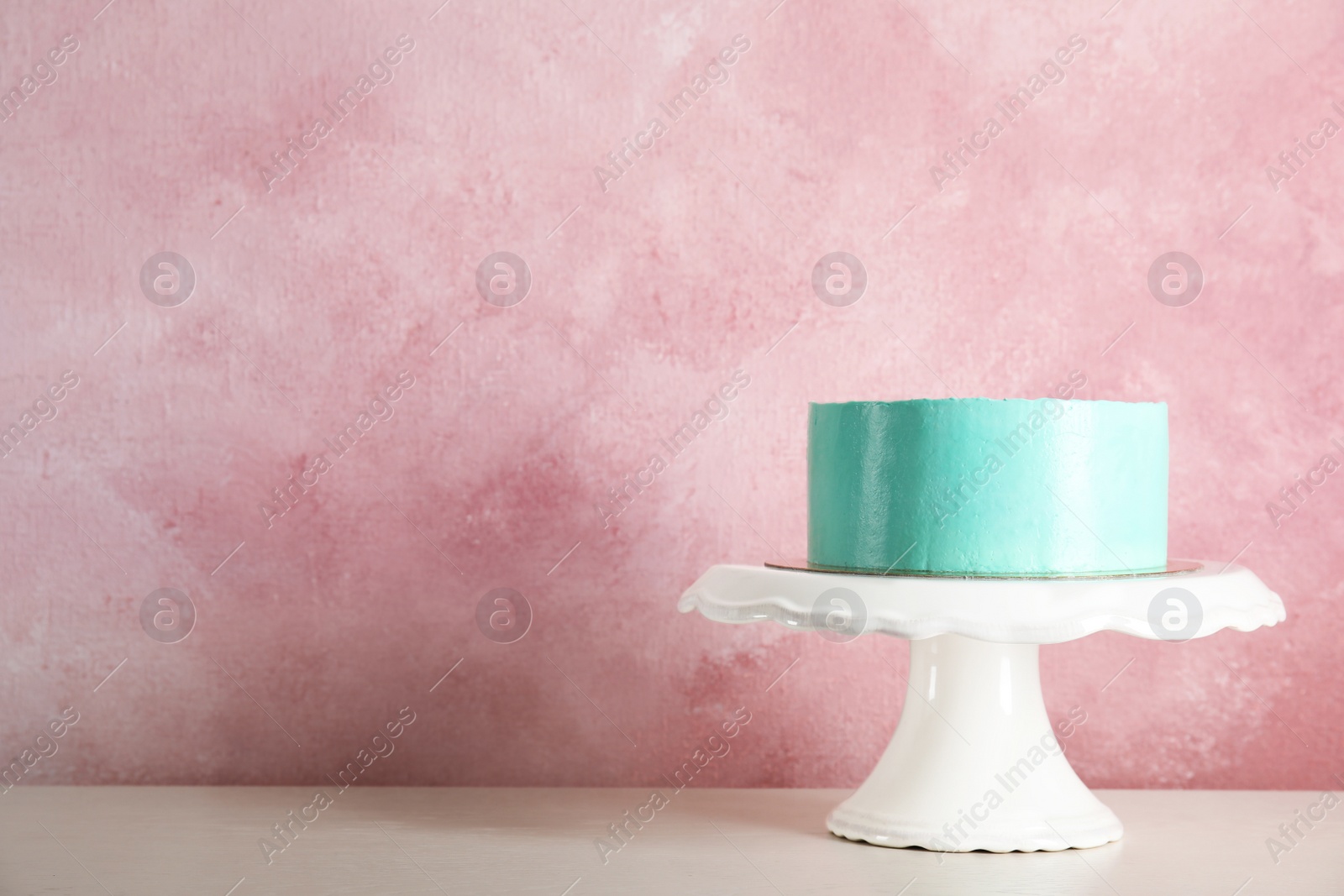 Photo of Fresh delicious birthday cake on stand against color background. Space for text