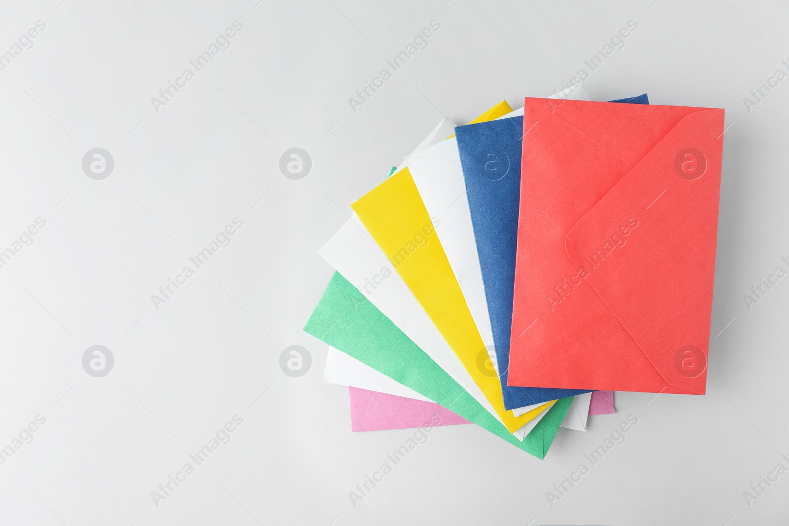 Photo of Colorful paper envelopes on light background, top view. Space for text