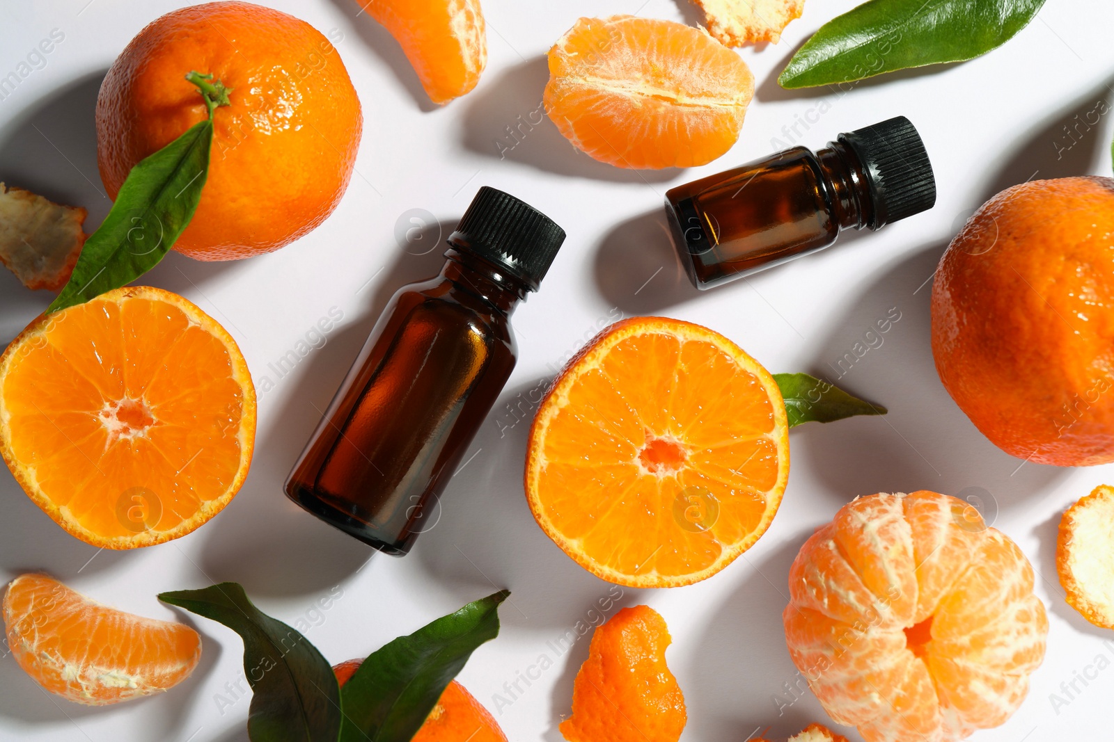 Photo of Aromatic tangerine essential oil in bottles and citrus fruits on white table, flat lay