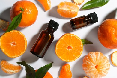 Aromatic tangerine essential oil in bottles and citrus fruits on white table, flat lay