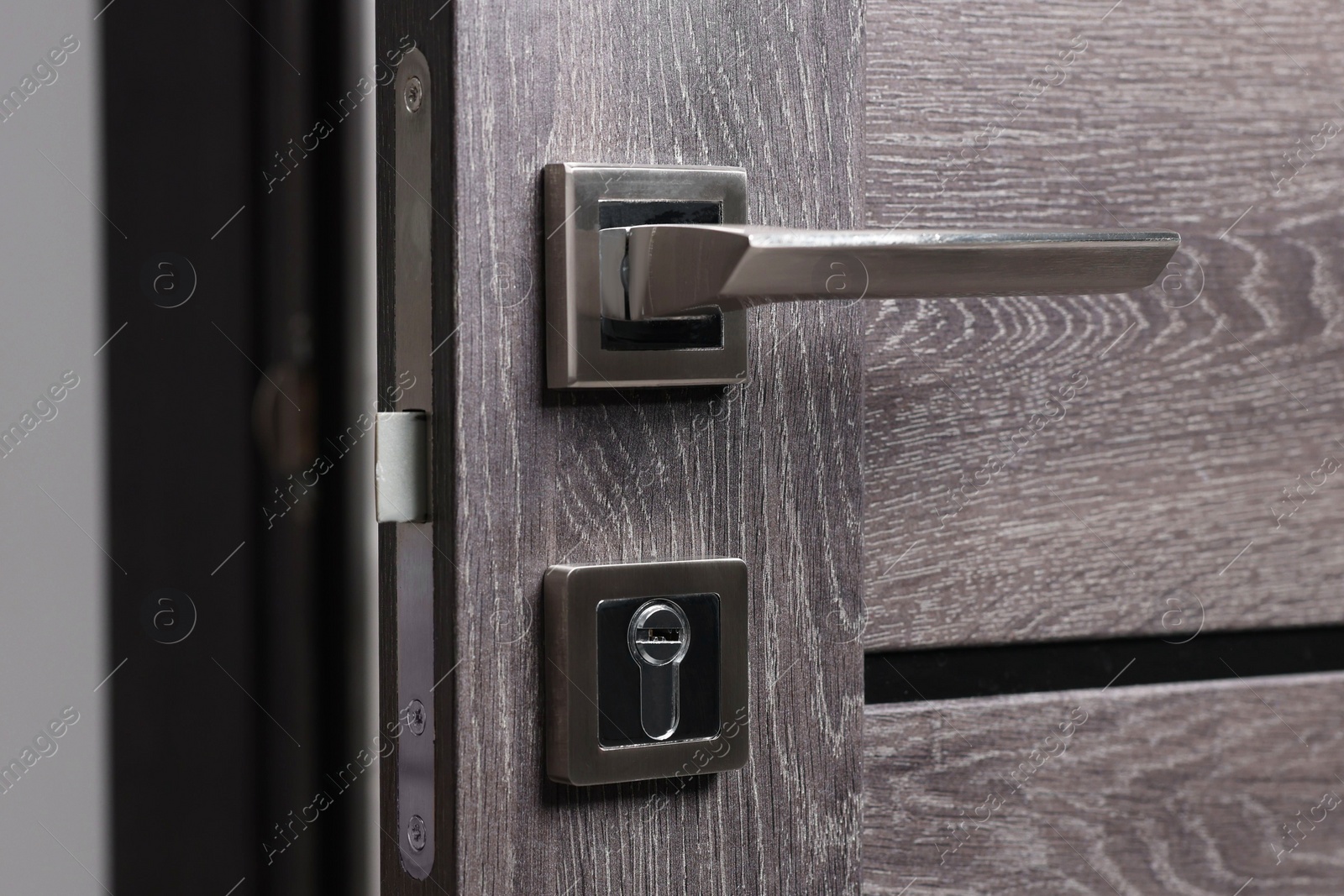 Photo of Open wooden door with metal handle, closeup