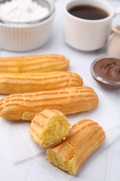 Photo of Delicious eclairs on white checkered table, closeup view