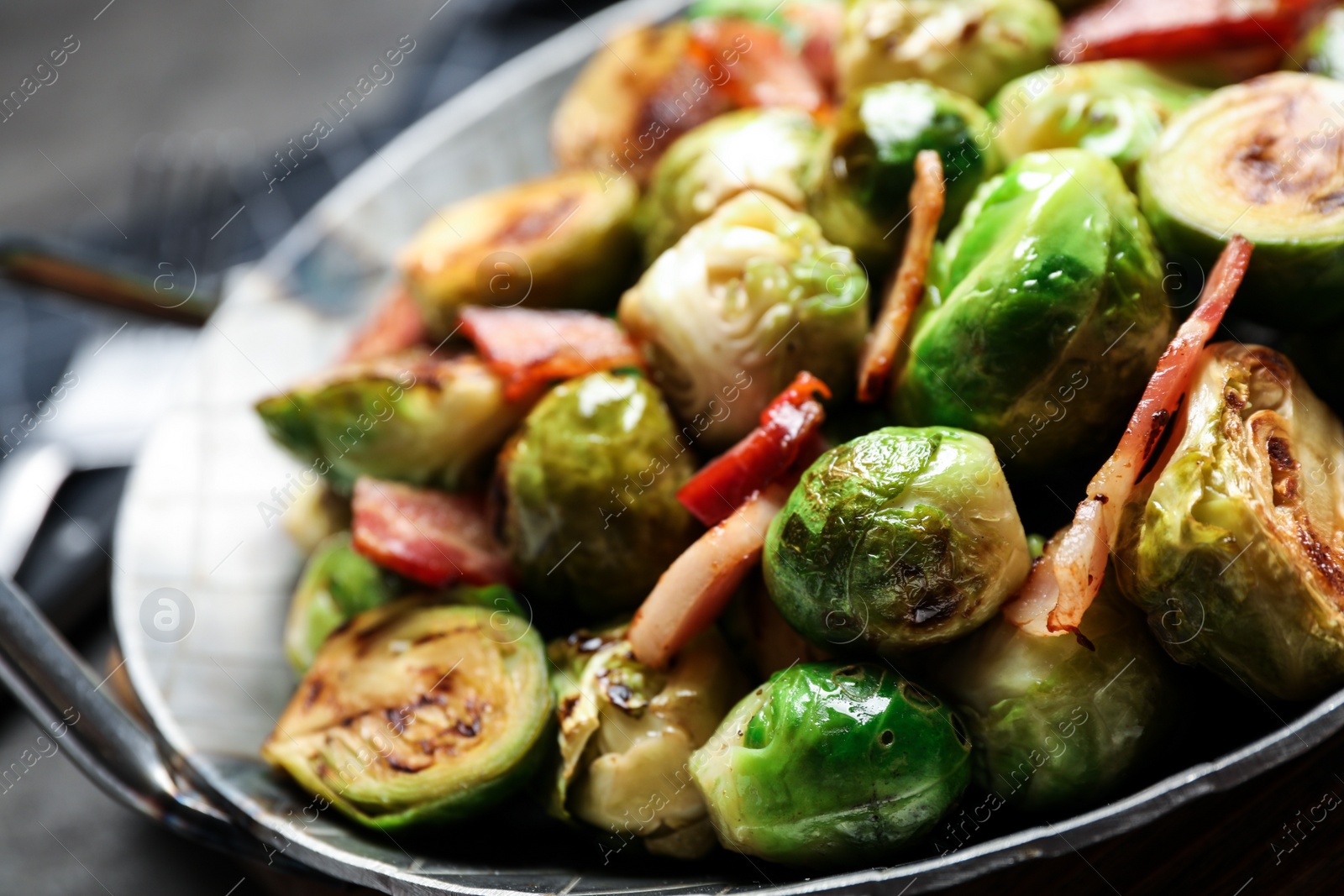 Photo of Delicious Brussels sprouts with bacon in dish on table, closeup