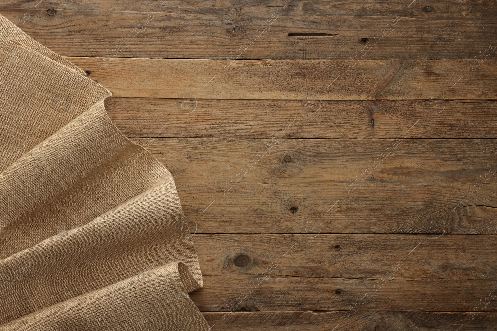 Photo of Burlap fabric on wooden table, top view. Space for text