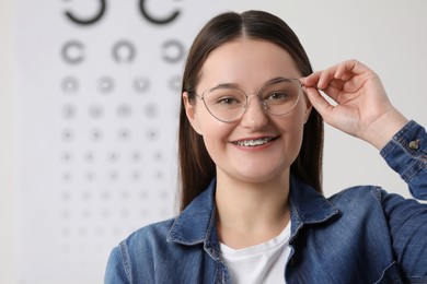 Photo of Young woman with glasses against vision test chart