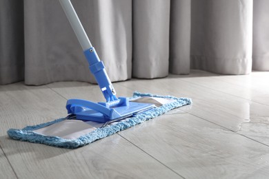 Photo of Cleaning white parquet floor with mop, closeup. Space for text