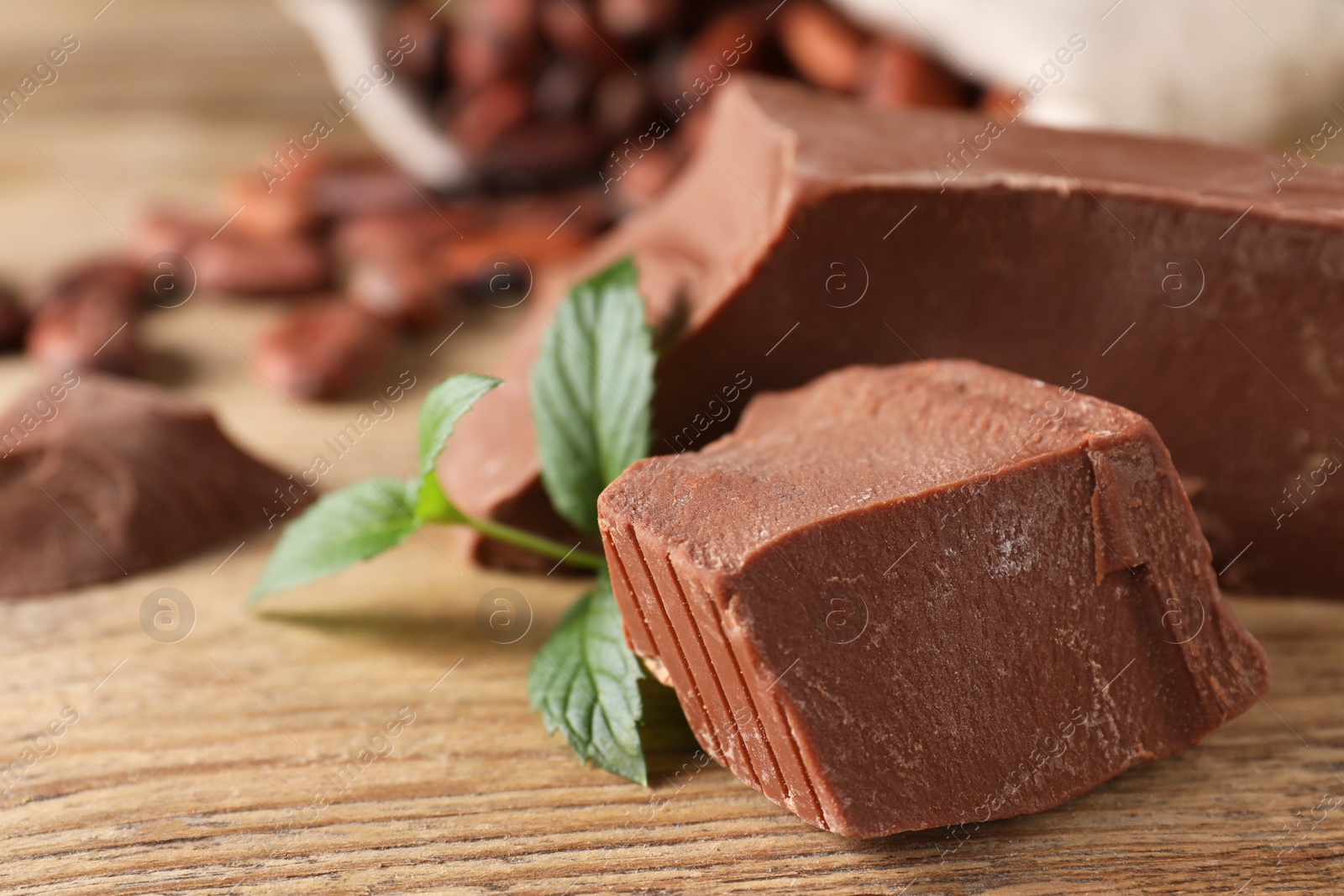 Photo of Pieces of tasty milk chocolate and mint on wooden table, closeup