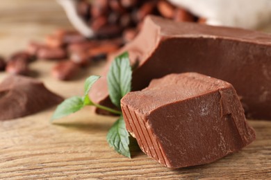 Photo of Pieces of tasty milk chocolate and mint on wooden table, closeup