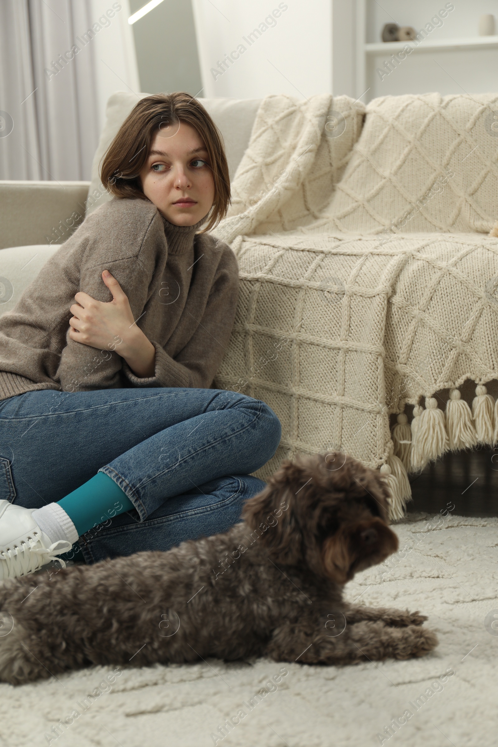 Photo of Sad young woman and her dog sitting on floor at home