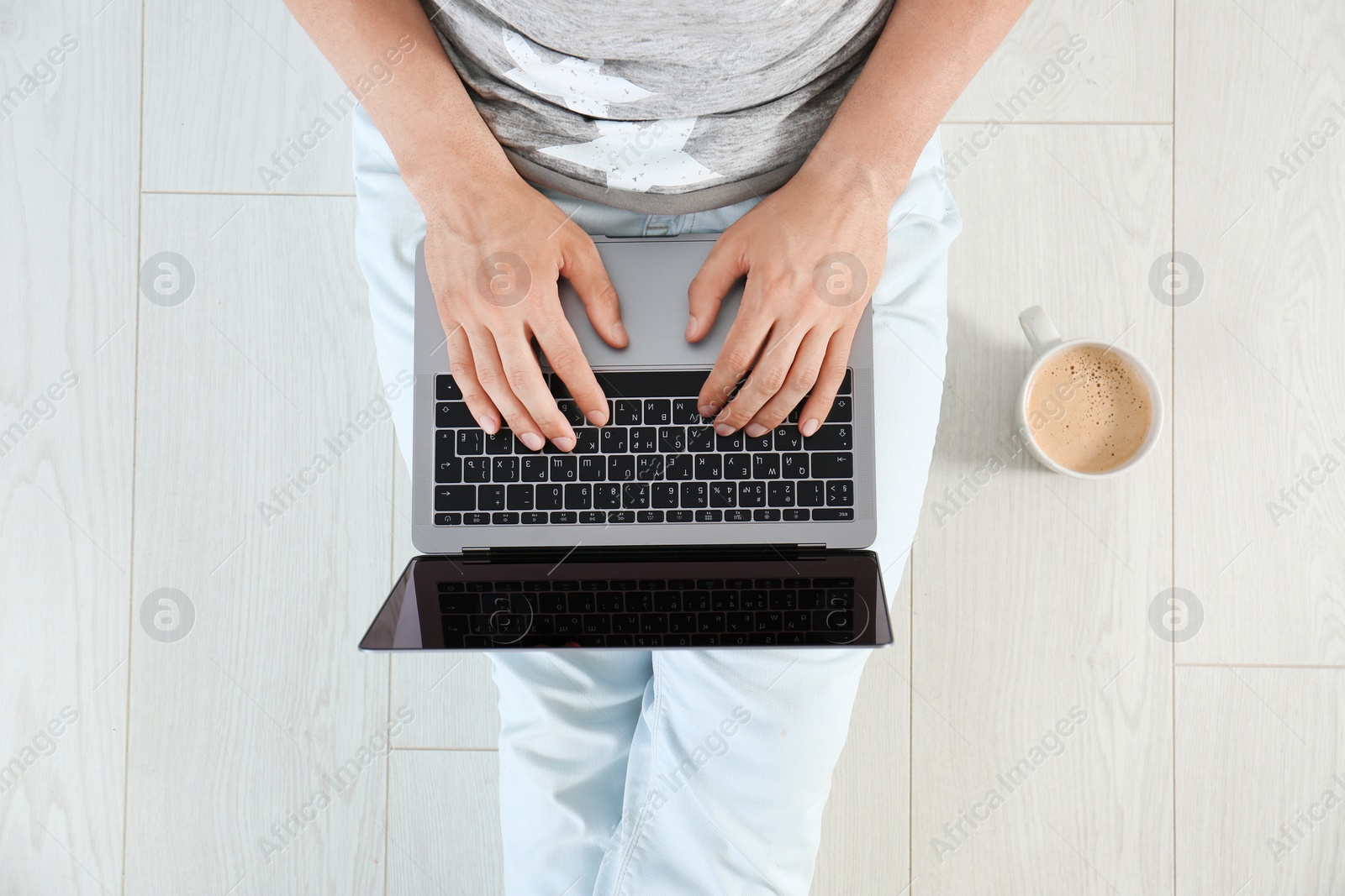 Photo of Young man with laptop sitting on floor, top view