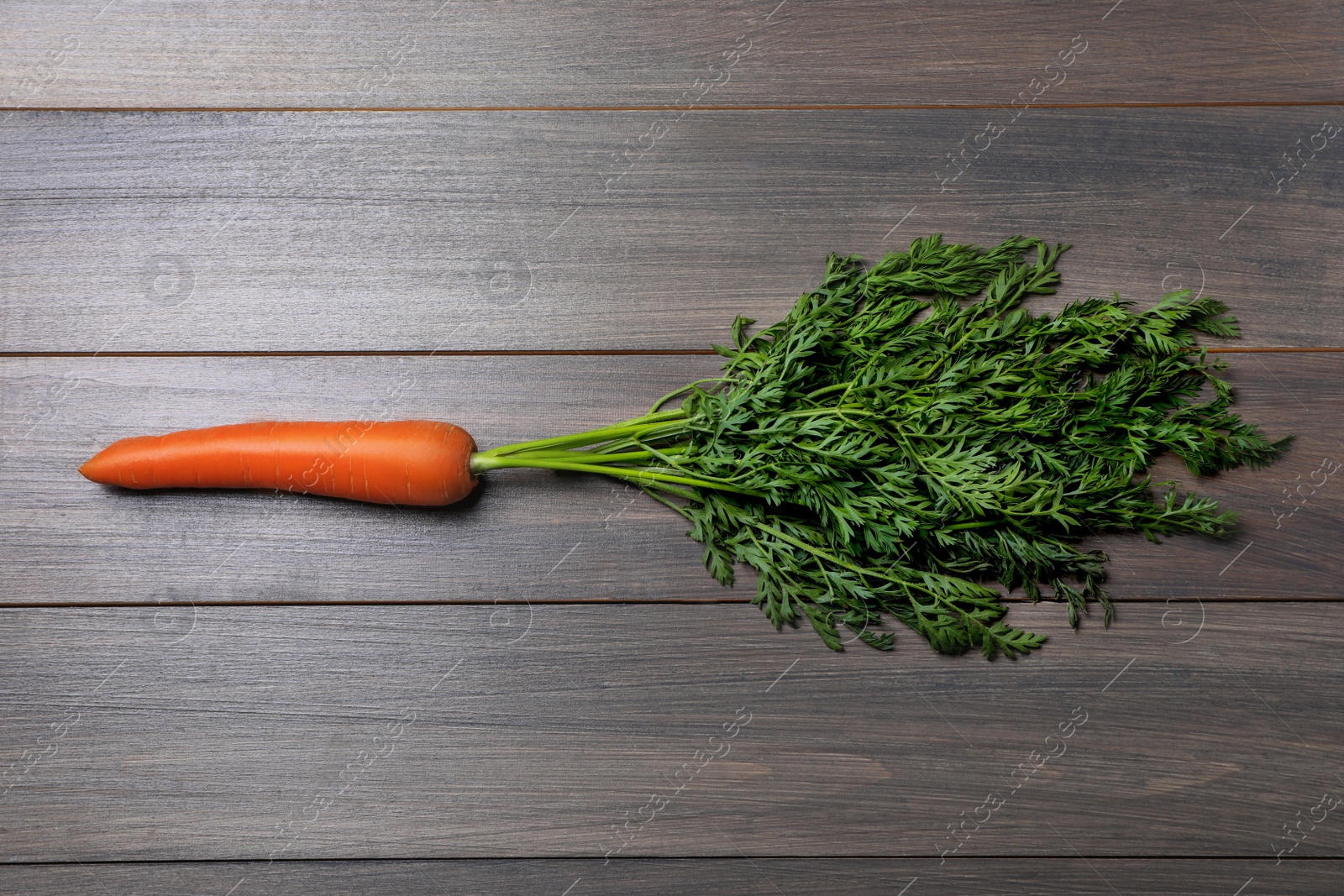 Photo of Tasty ripe carrot on wooden table, top view