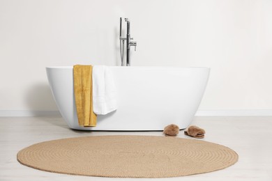 Photo of Stylish bathroom interior with ceramic tub and terry towels