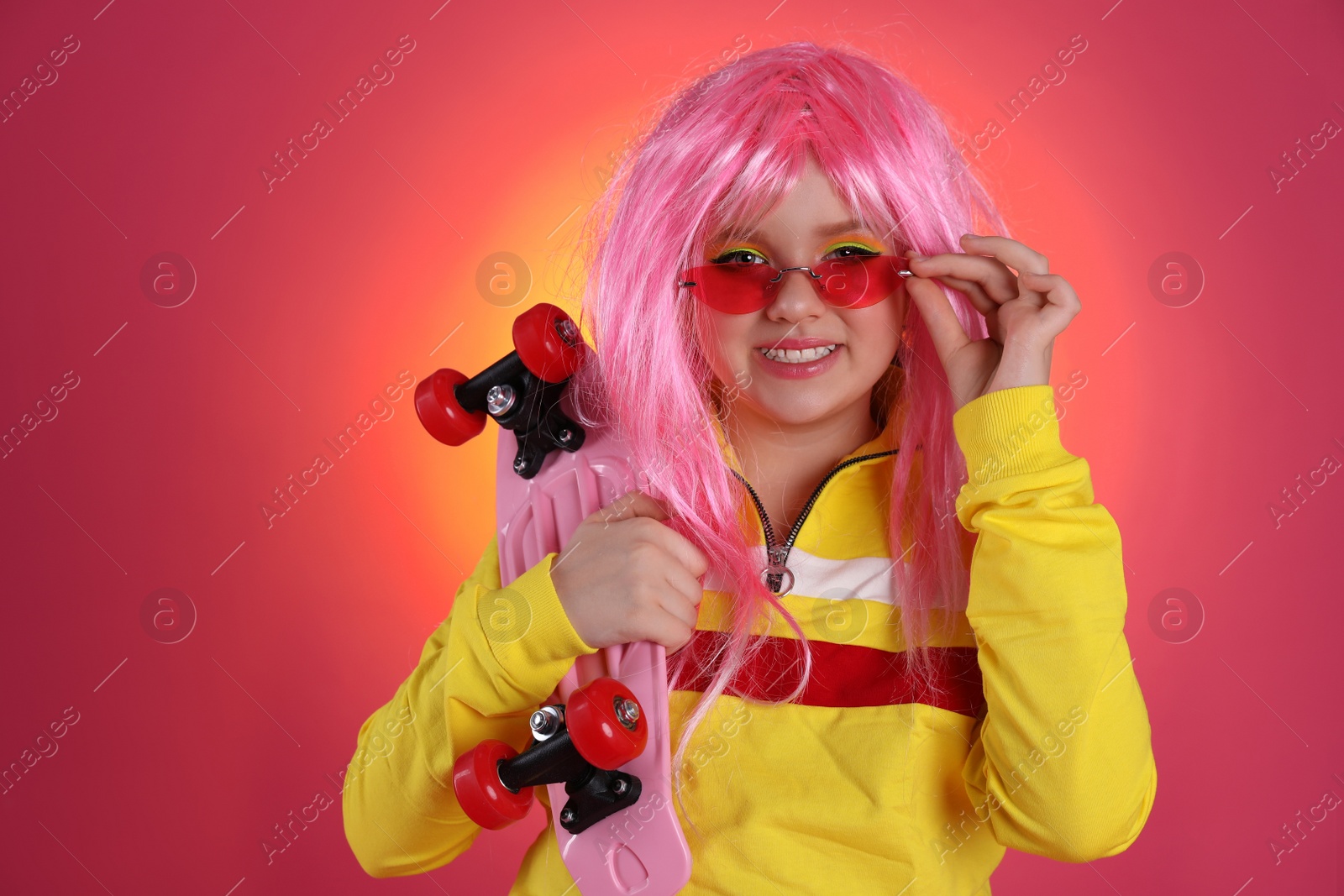 Photo of Cute indie girl with sunglasses and penny board on bright pink background, space for text