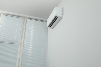 Photo of Modern air conditioner on white wall indoors, low angle view. Space for text