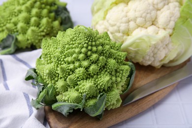 Photo of Fresh Romanesco broccoli and cauliflower on white tiled table, closeup