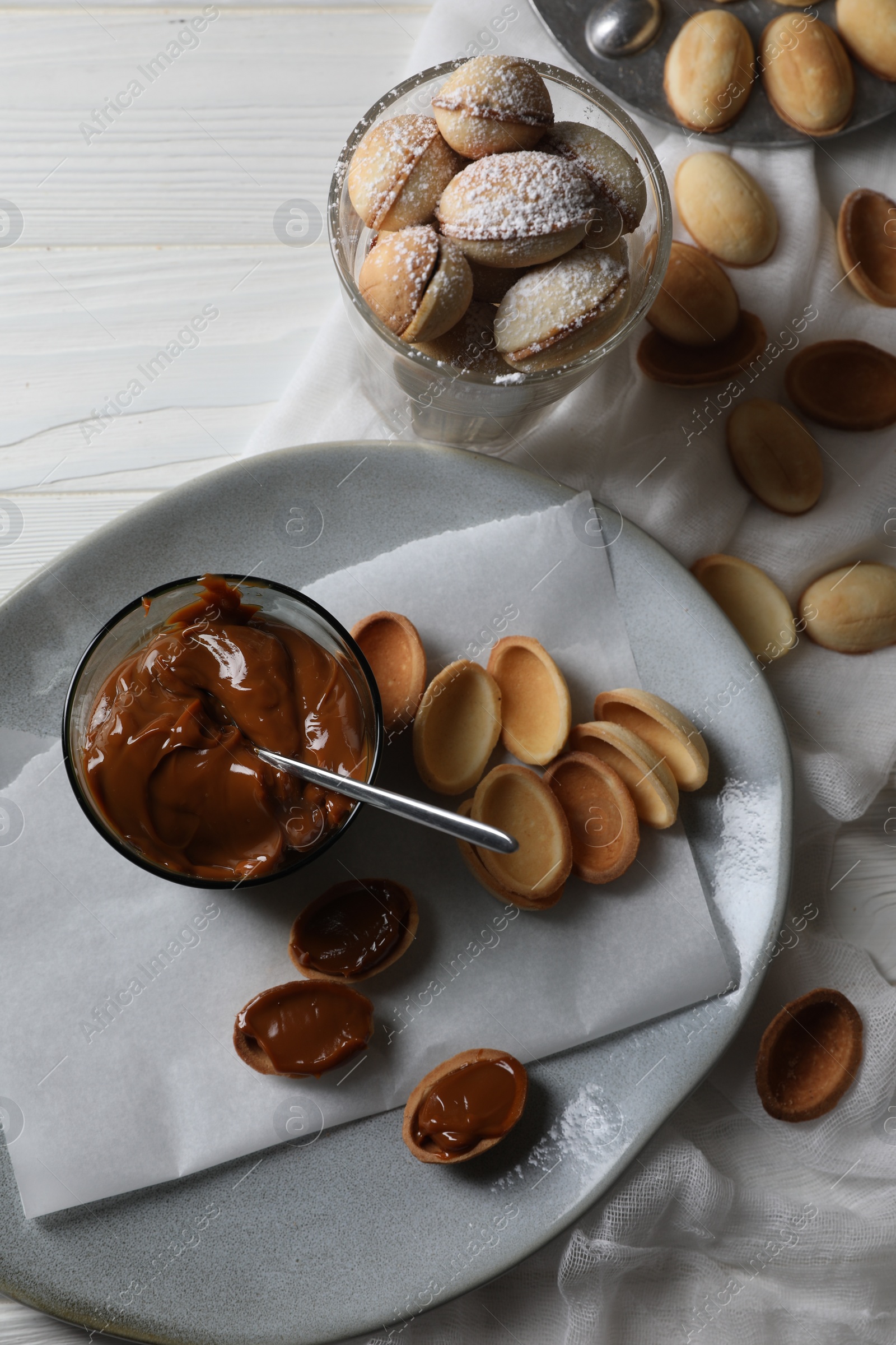 Photo of Delicious walnut shaped cookies with condensed milk on white wooden table, flat lay