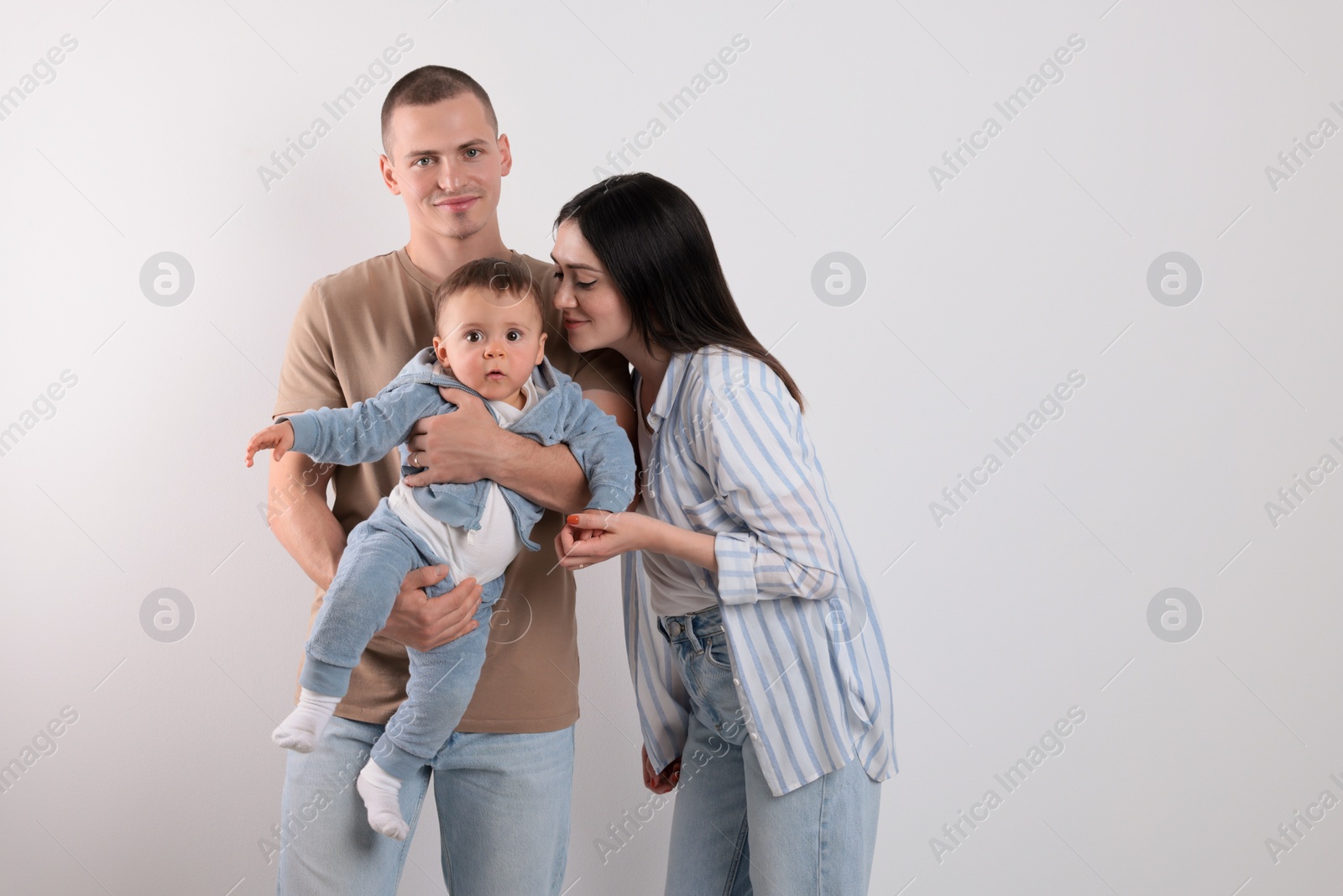 Photo of Portrait of happy family with little child on light background. Space for text