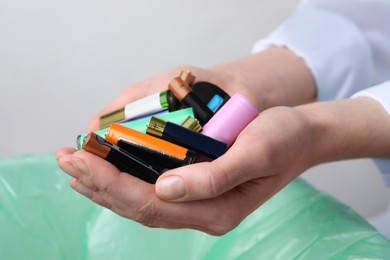 Woman holding many used electric batteries in her hands, closeup