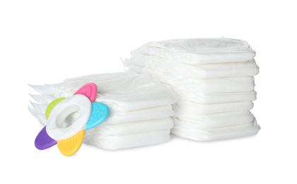 Photo of Disposable diapers and teether on white background